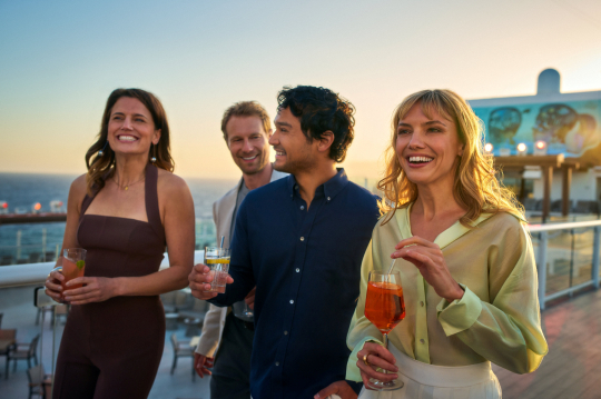 Vierergruppe mit Drinks in der Hand auf Deck eines Mein Schiff Kreuzfahrtschiffes